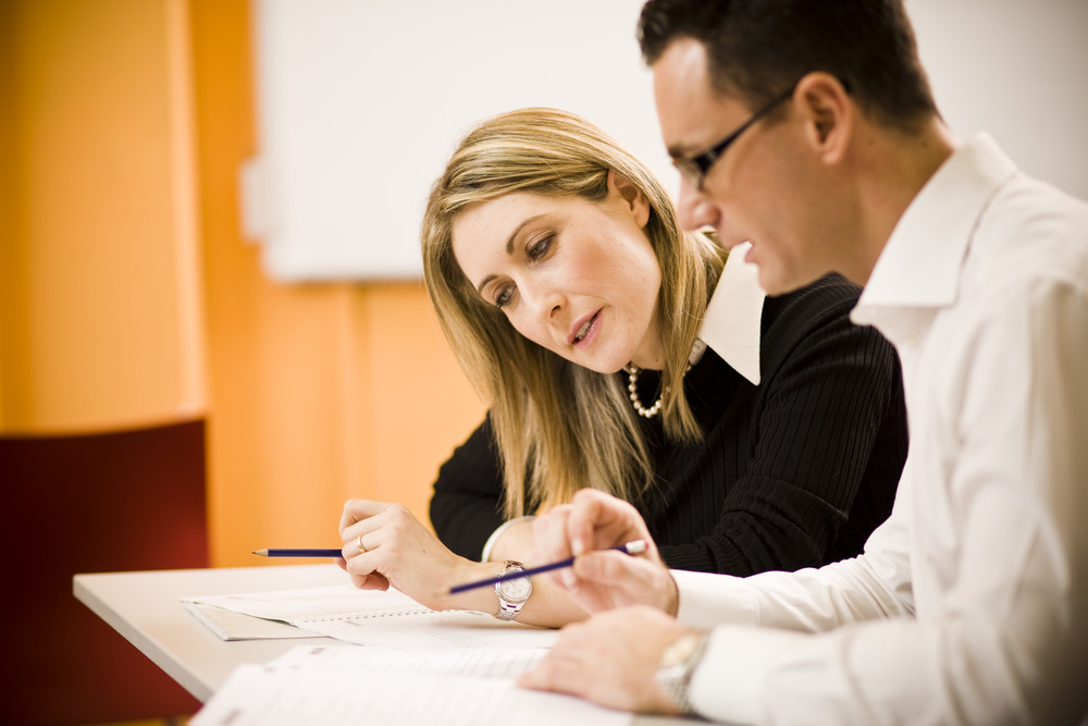A woman and man sitting at a table with papers.