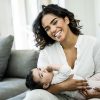 Smiling mother holding her baby on couch.